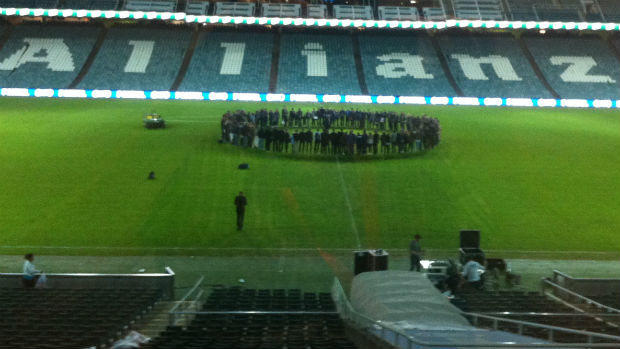 Sydney FC players and their families form a huddle on Allianz Stadium after full-time.